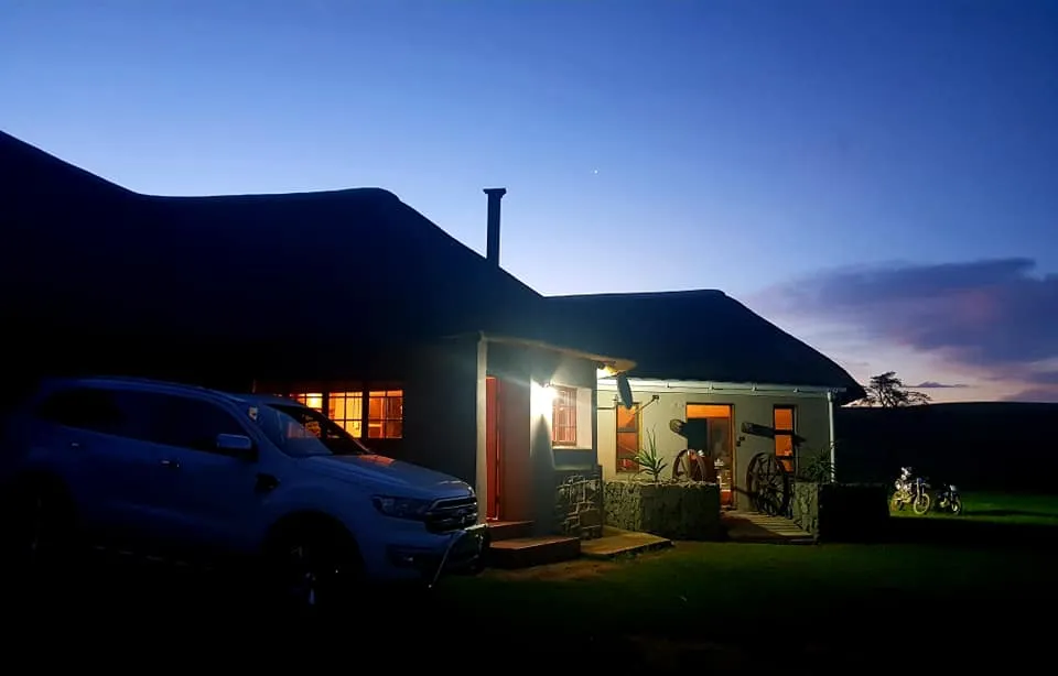 House with lights on at dusk car parked in front grassy area