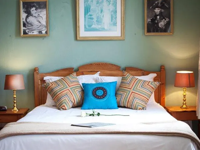 Bedroom with a neatly made bed colorful pillows and framed pictures on the wall
