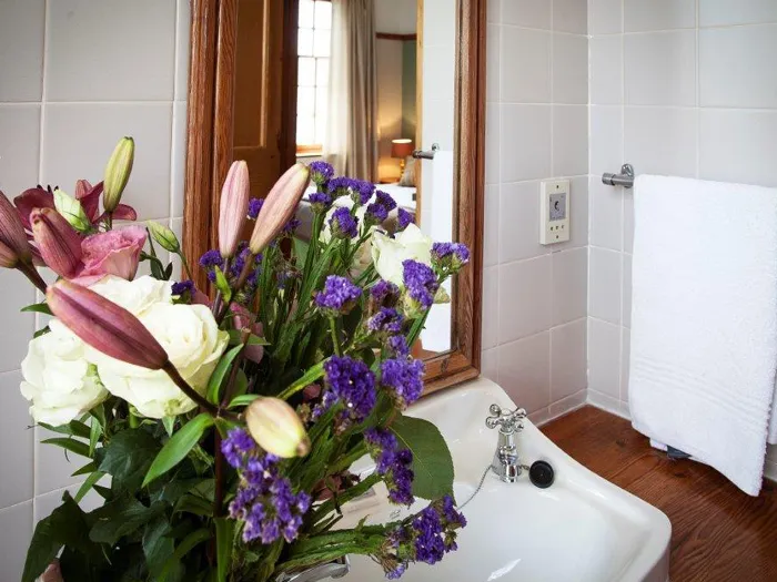 Bouquet of flowers in a vase on a bathroom sink with a towel