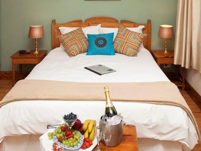 Bed with pillows fruit platter and champagne bucket on a bedside table