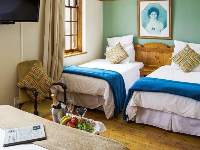Two beds in a cozy bedroom with wooden floor and a fruit basket