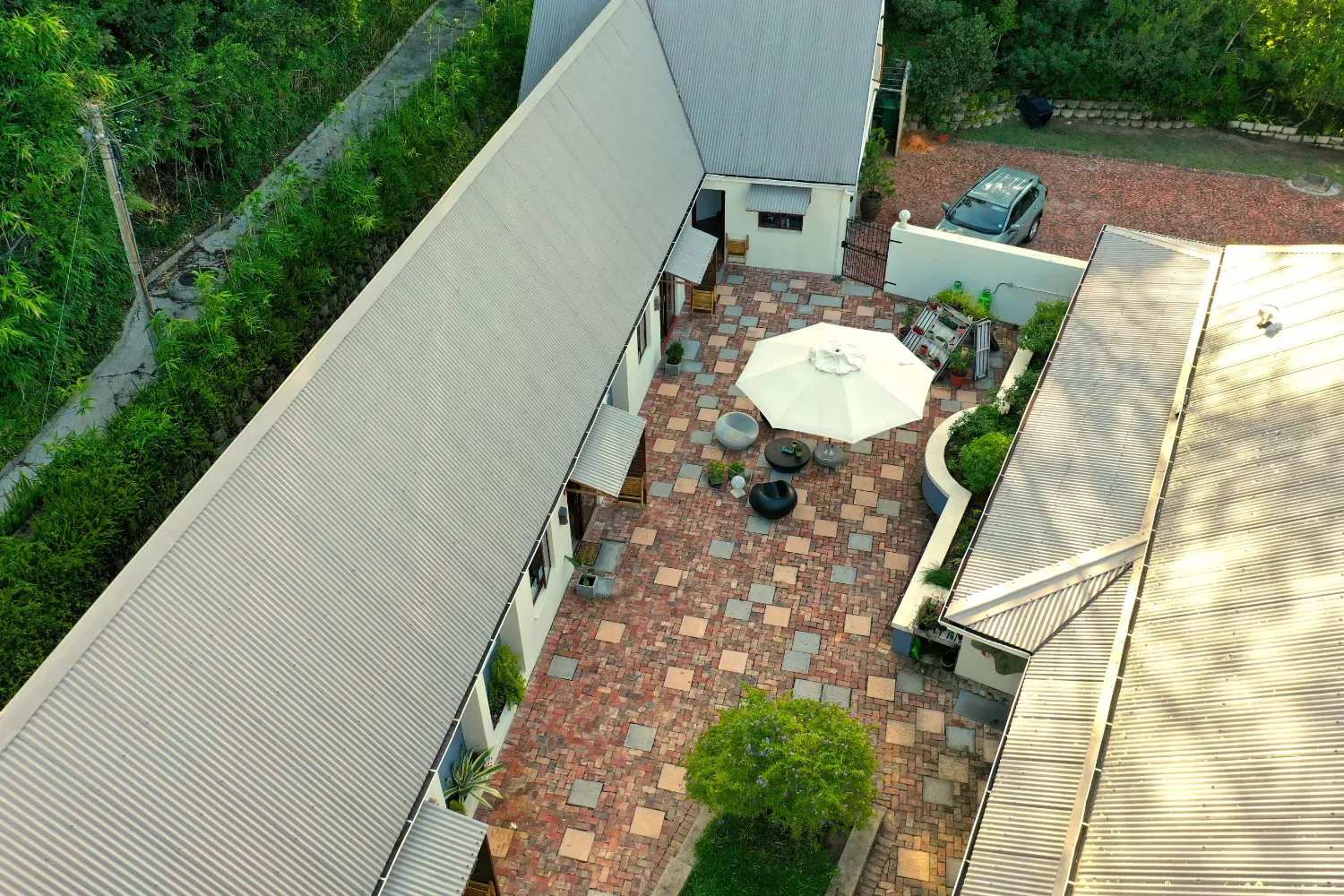 Aerial view of a house with a courtyard patio furniture and surrounding greenery