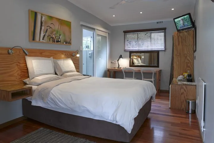 Modern hotel room with bed desk TV and wooden flooring