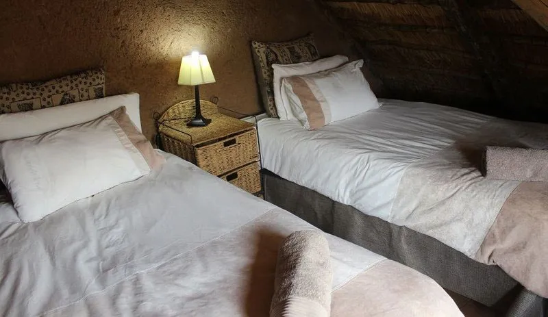 Two single beds in a cozy rustic room with a bedside lamp