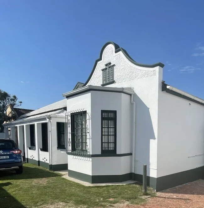 White and green house with a gable facade and a clear blue sky