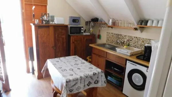 Small kitchen with wooden table sink microwave and washing machine under slanted ceiling