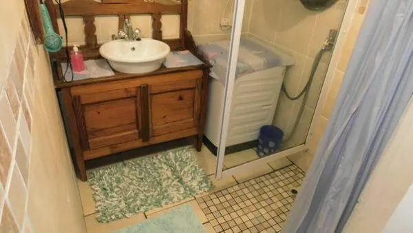 Compact bathroom with wooden sink cabinet shower and tiled floor