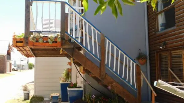 Wooden staircase leading to a balcony with potted plants on a house exterior