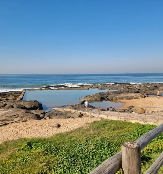 Rocky beach with tide pool clear blue sky and ocean waves in background