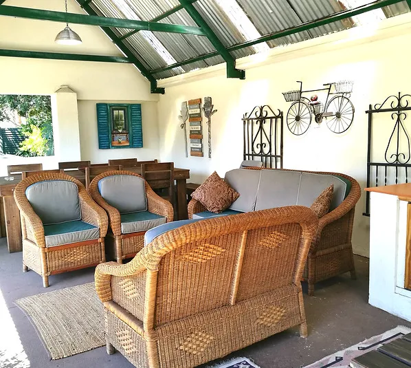 Wicker furniture on a patio with a corrugated metal roof and decorative wall items