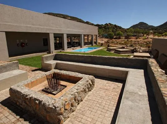Modern outdoor seating area with fire pit and pool desert landscape in background