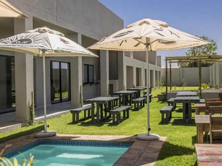 Outdoor seating area with tables chairs umbrellas and a small pool