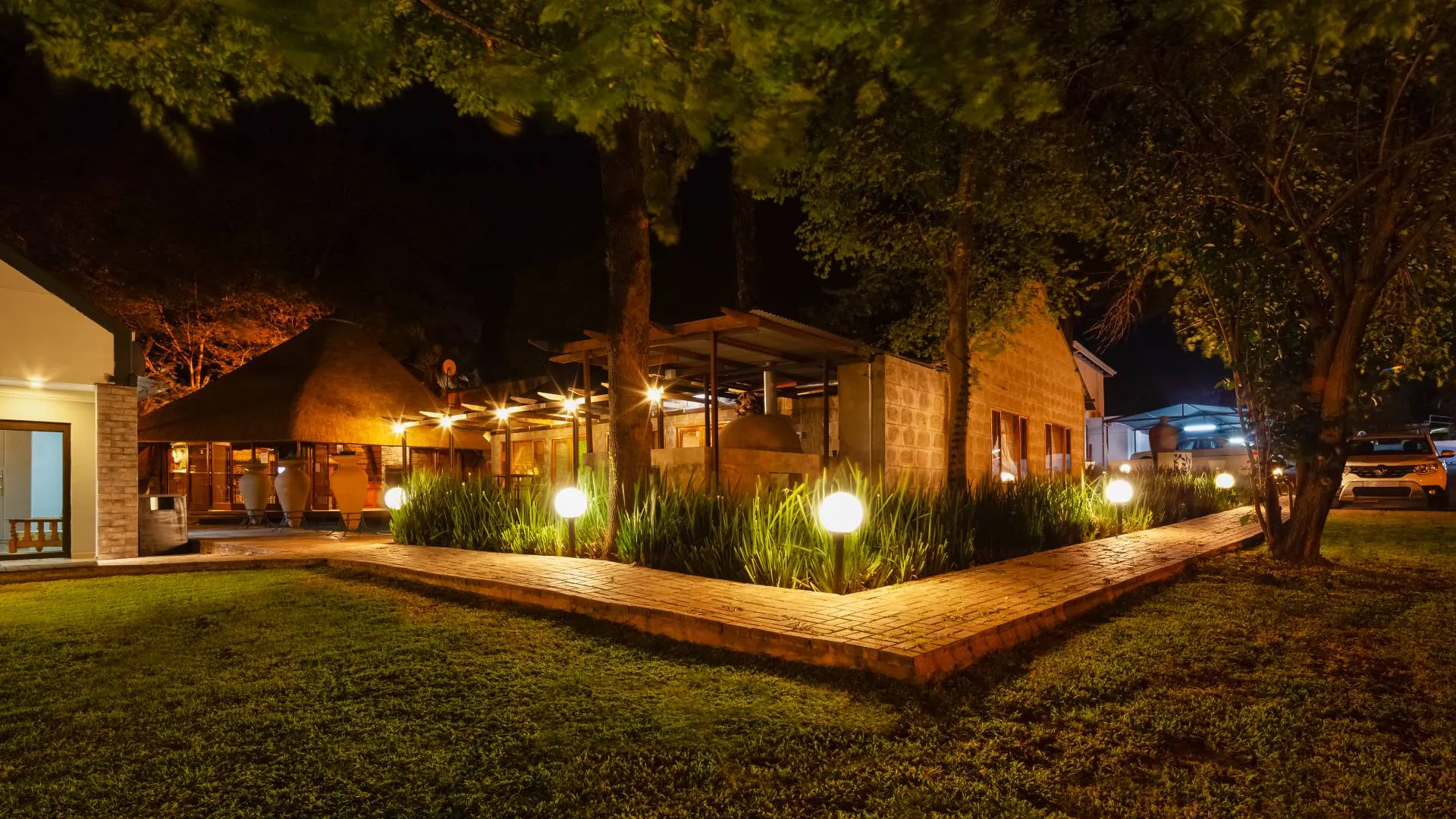 Outdoor restaurant at night with warm lighting and lush greenery
