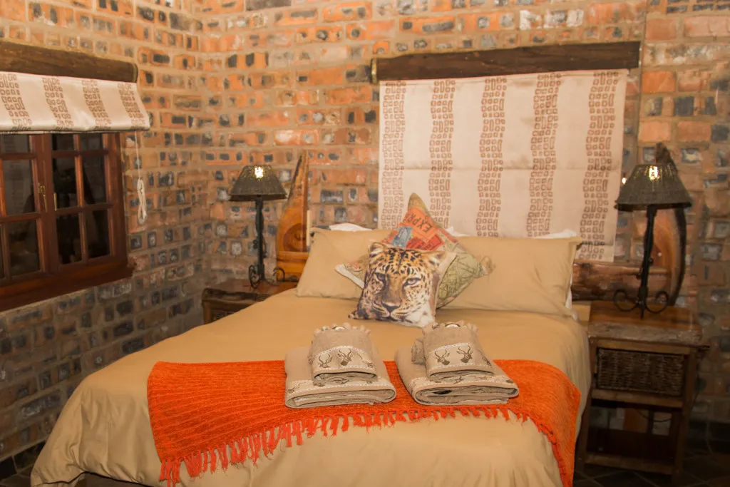 Cozy bedroom with a bed orange blanket and brick walls with wooden accents