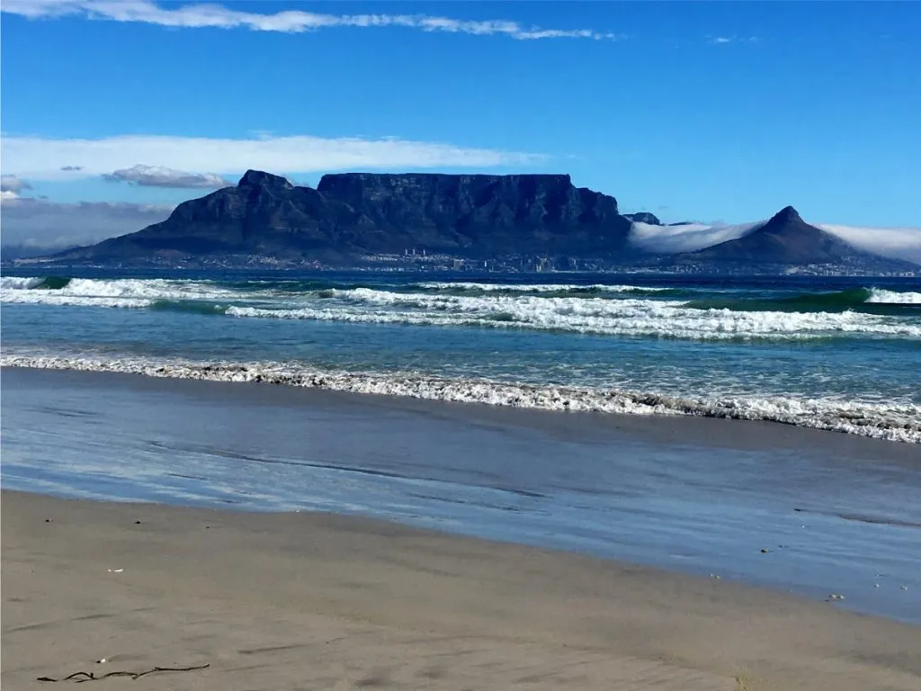 Beach with waves sandy shore and a large mountain in the background
