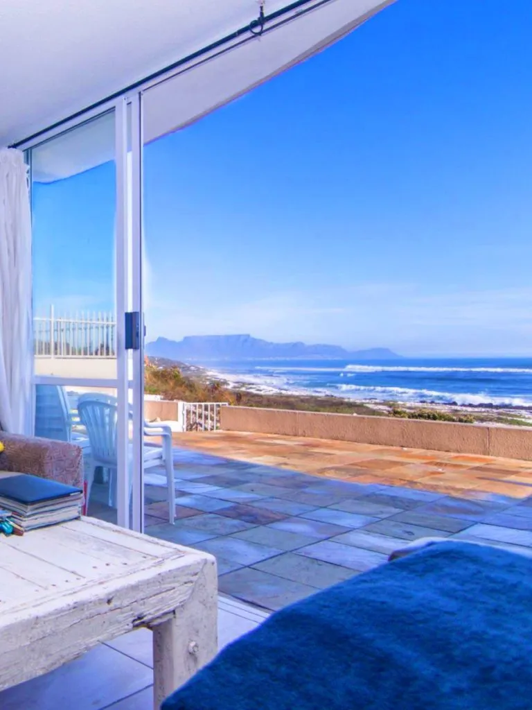 Living room with large sliding doors opening to a patio with ocean view