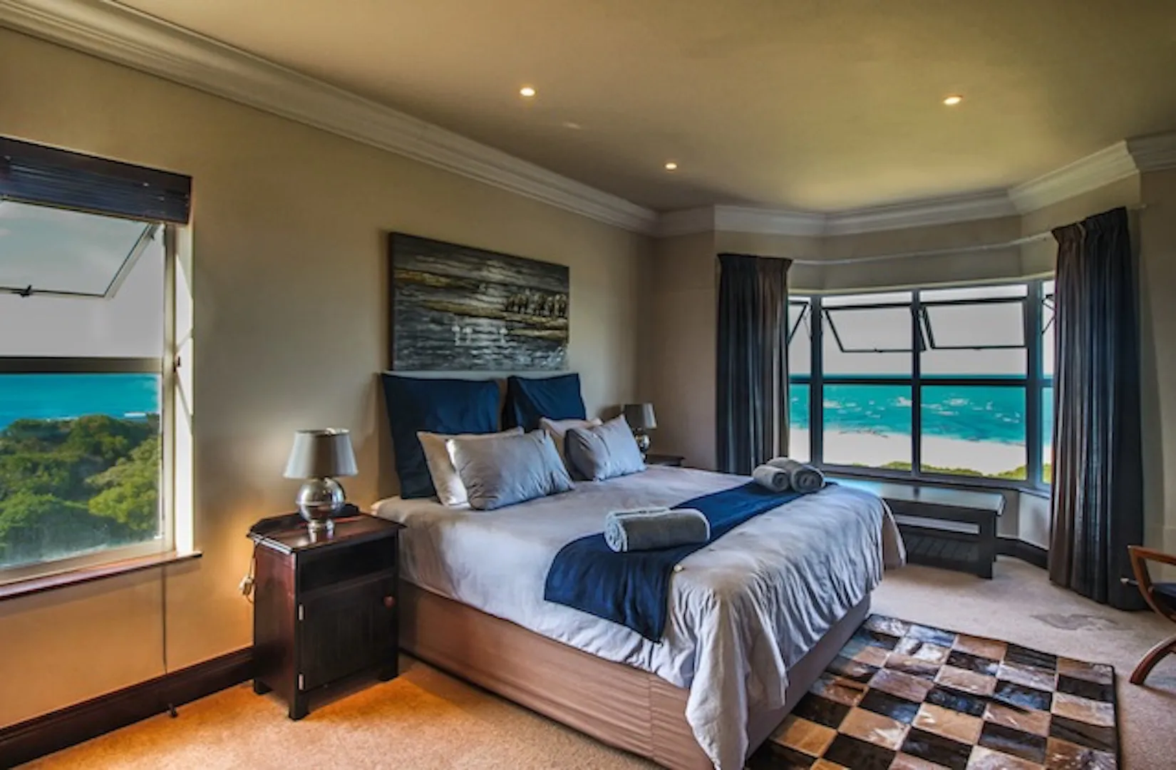 Bedroom with large bed ocean view windows and modern decor