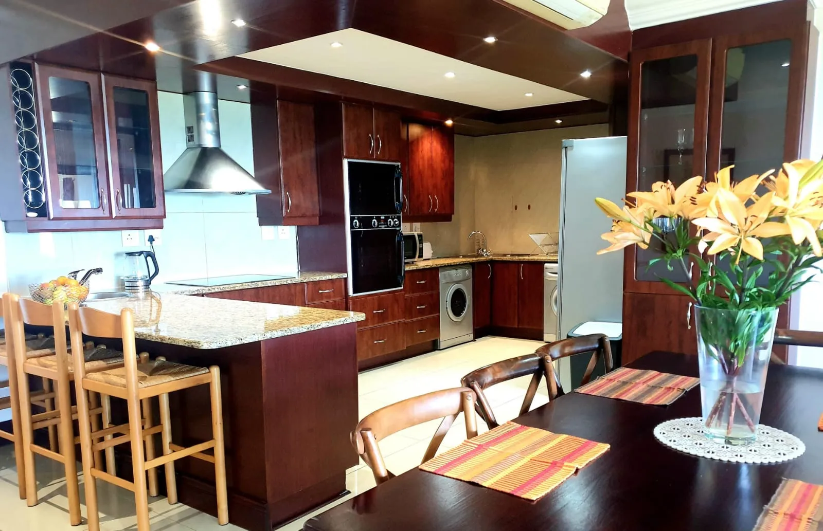 Modern kitchen with wooden cabinets black appliances and dining area with yellow flowers