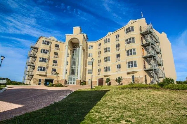 Modern beige apartment building with blue sky and green lawn in front