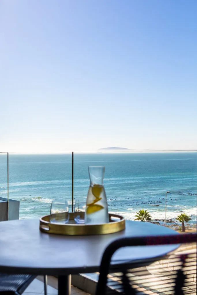 Tray with pitcher and glasses on table overlooking ocean and beach
