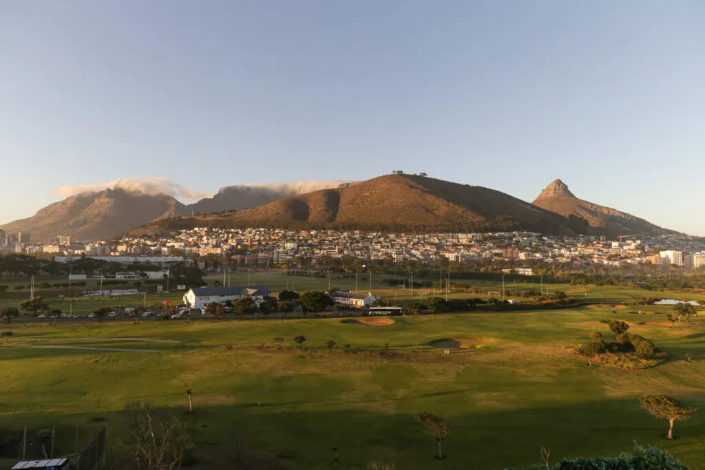 Cityscape with mountains in the background and green fields in the foreground