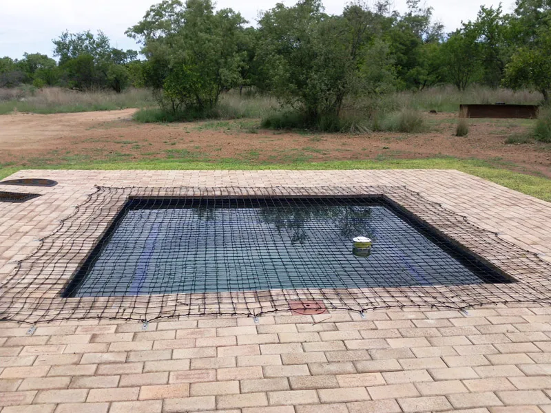 Small pool with safety net in a garden surrounded by brick paving