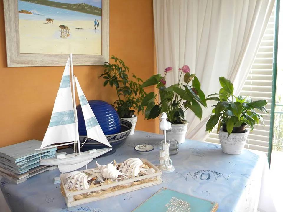 Model sailboat and potted plants on a decorated table with a beach painting