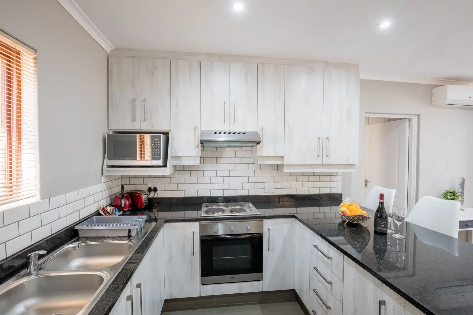 Modern kitchen with white cabinets black countertops and stainless steel appliances