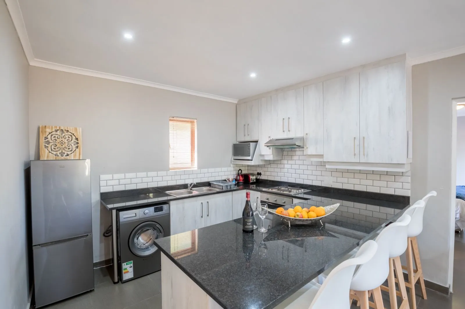 Modern kitchen with black countertops white cabinets and breakfast bar with stools