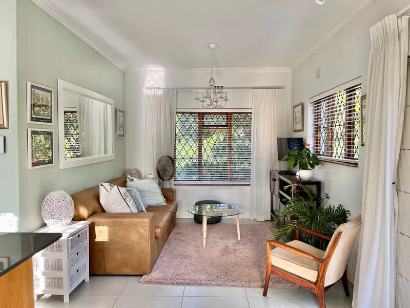 Cozy living room with leather sofa armchair and large windows with curtains