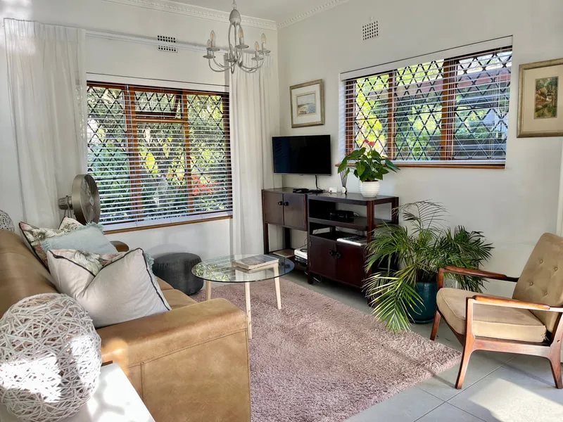 Cozy living room with sofa armchair TV plants and large windows