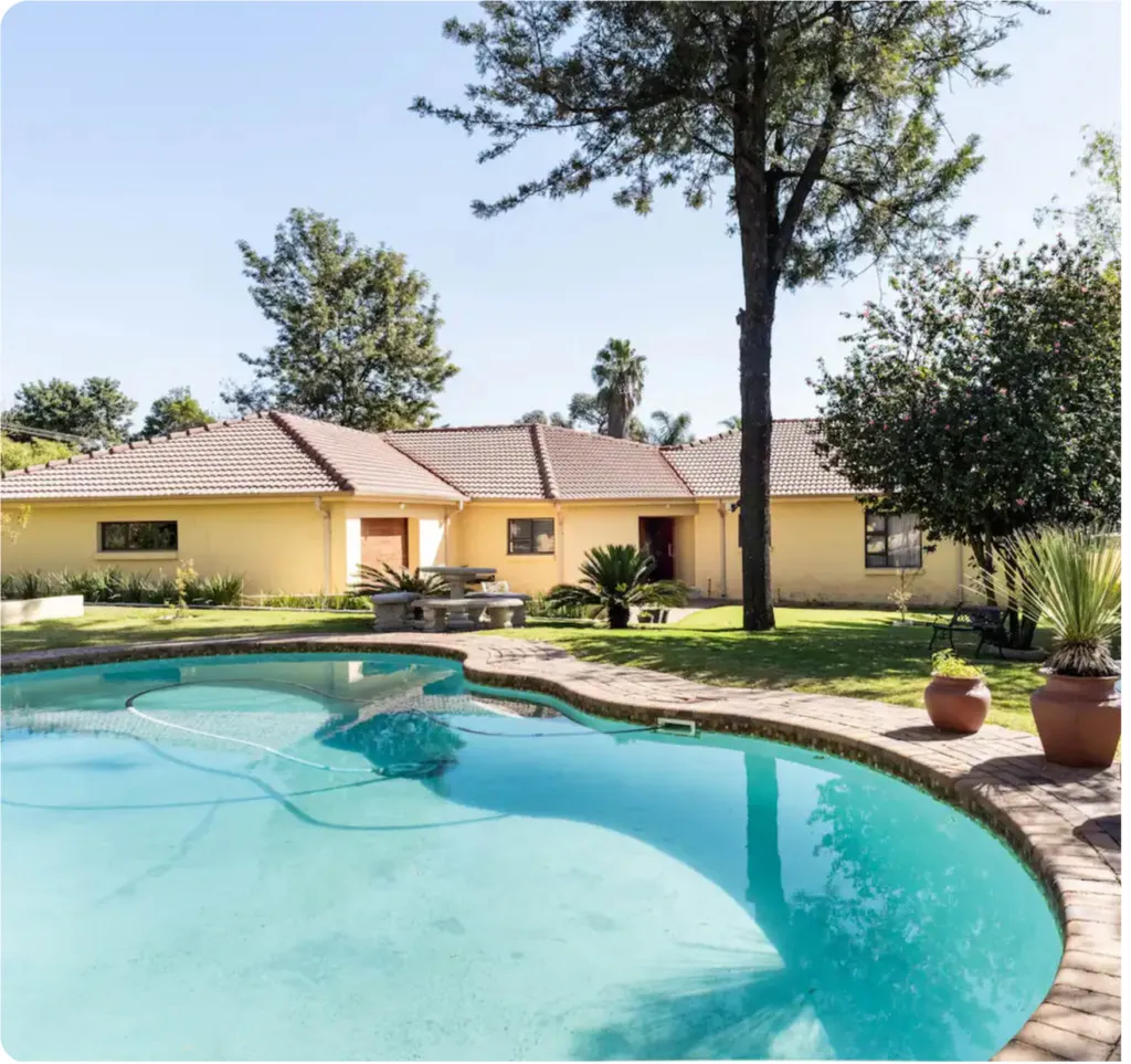 Yellow house with a swimming pool and garden in a sunny setting