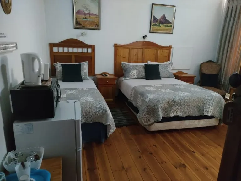 Two single beds in a bedroom with wooden floors and bedside tables