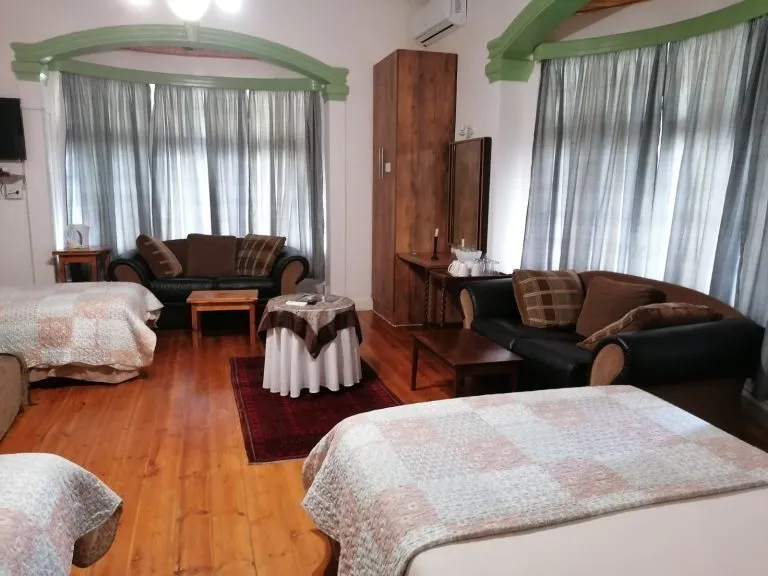 Cozy room with two beds sofas and large windows with curtains