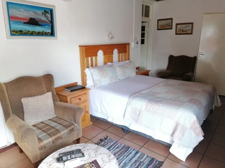 Cozy bedroom with double bed armchair and small table with remotes