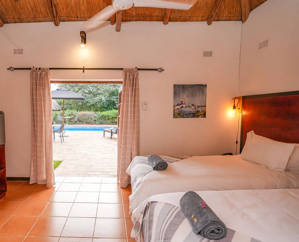 Bedroom with two beds open patio door and view of outdoor pool area