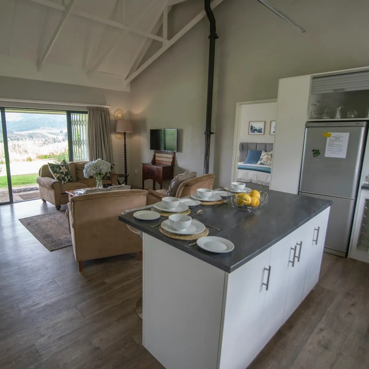 Modern kitchen with island living room and view of green fields through large windows