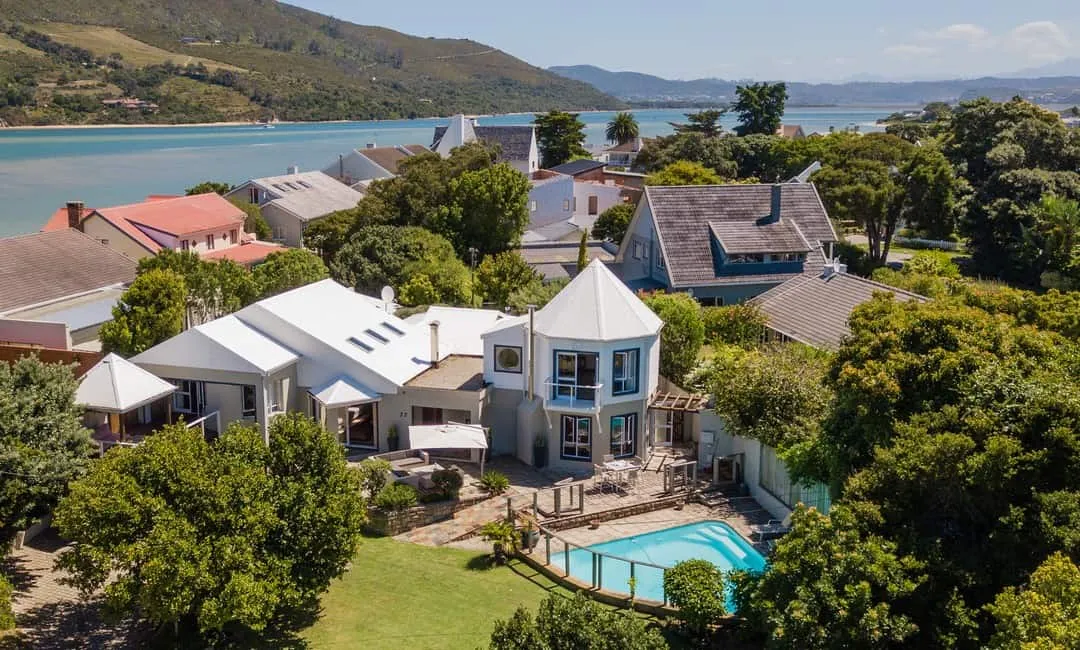 Aerial view of houses with a pool near a lake and hills
