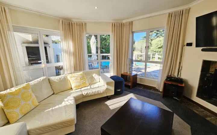 Bright living room with sectional sofa large windows and view of pool outside