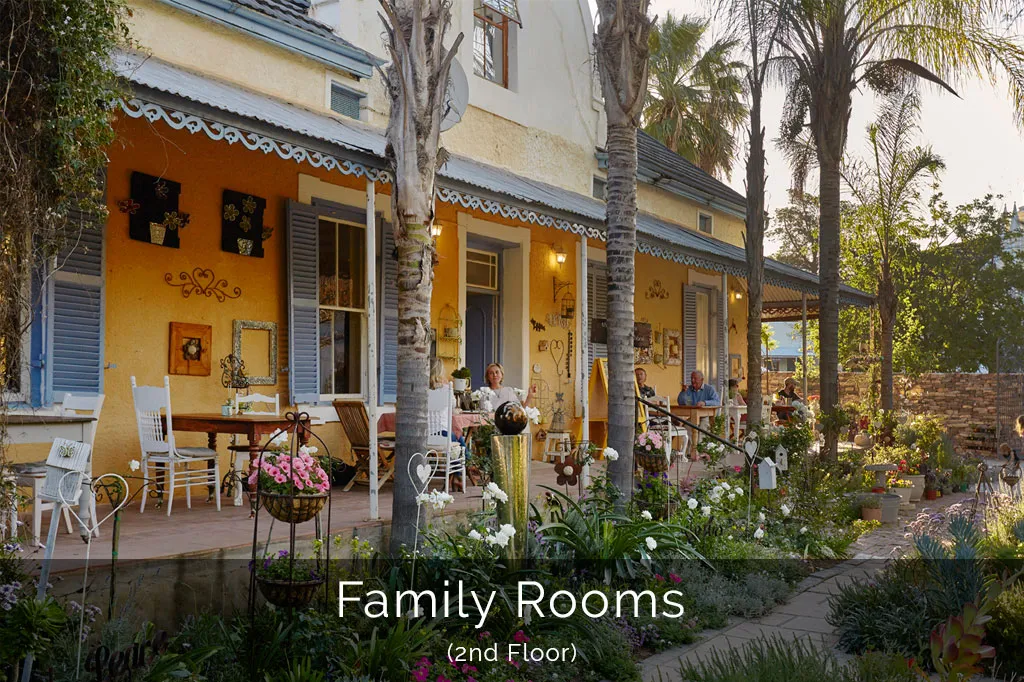 Yellow building with white trim palm trees and outdoor seating area with flowers