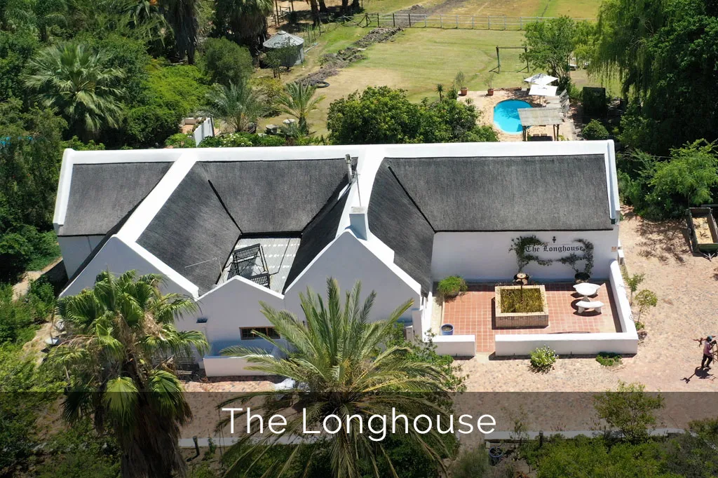 Aerial view of a white house with a garden and swimming pool
