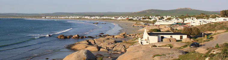 Rocky coastline with small buildings and a beach in the background