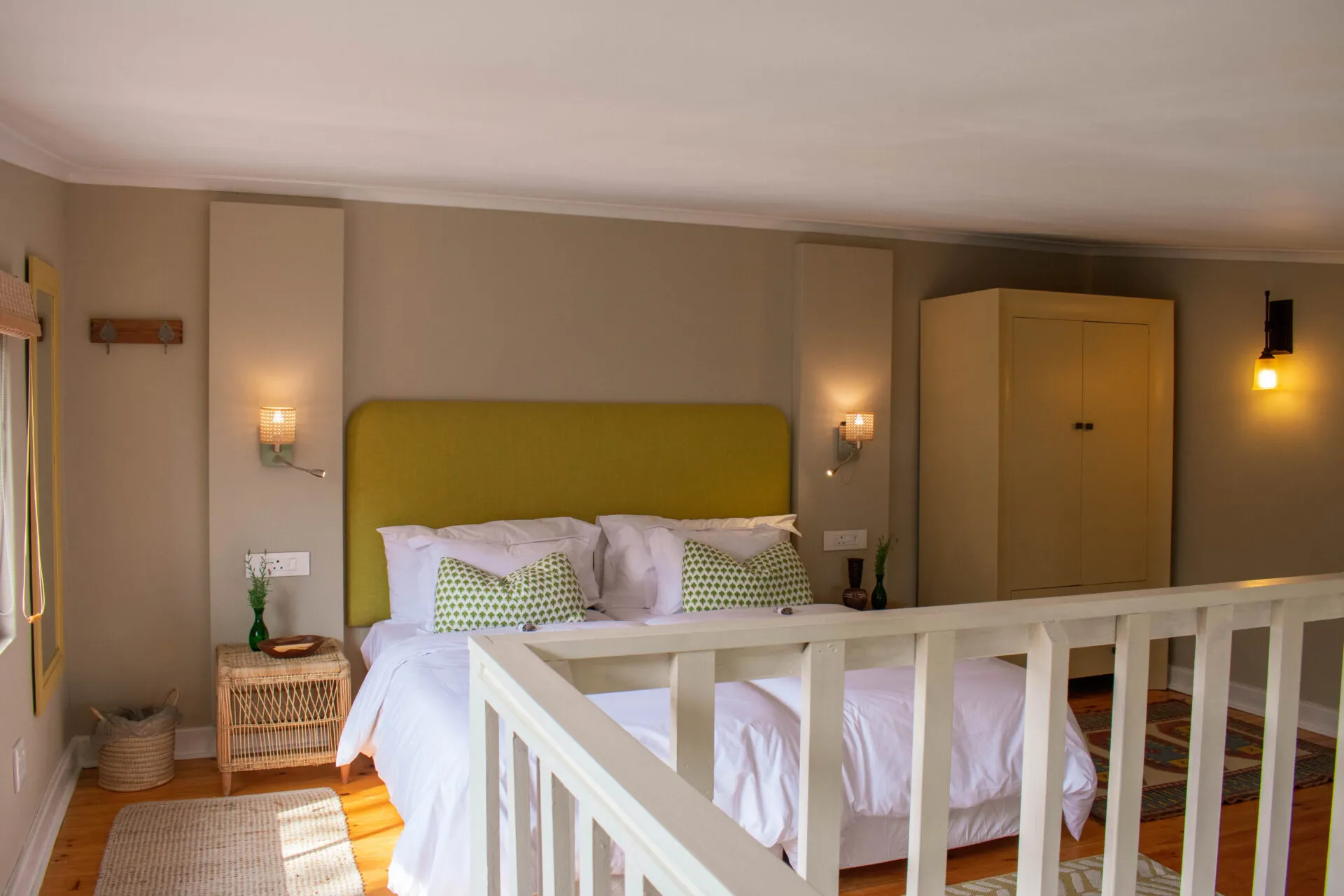 Bright bedroom with yellow headboard white bedding and wooden wardrobe