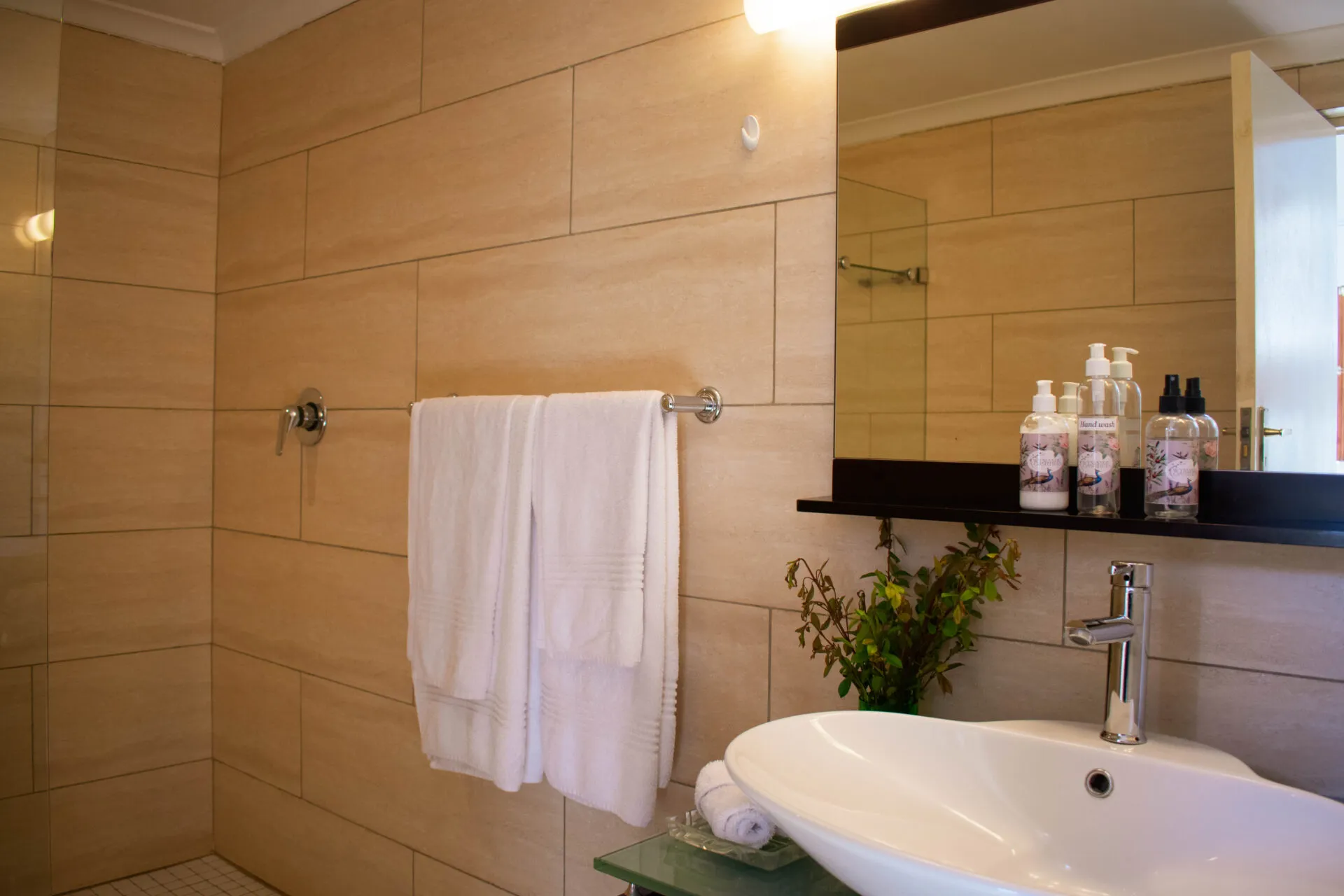 Modern bathroom with sink mirror towels and toiletries on a shelf
