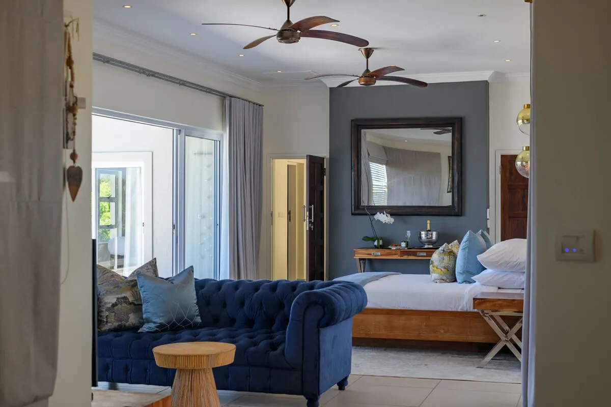 Blue velvet sofa and bed in a modern stylish bedroom with ceiling fans