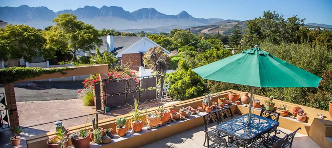 Patio with green umbrella potted plants and mountain view in the background