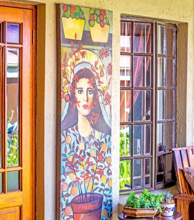 Colorful painting of a woman with flowers on a wall beside a window