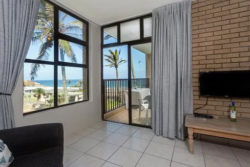 Living room with large windows ocean view and brick wall with TV