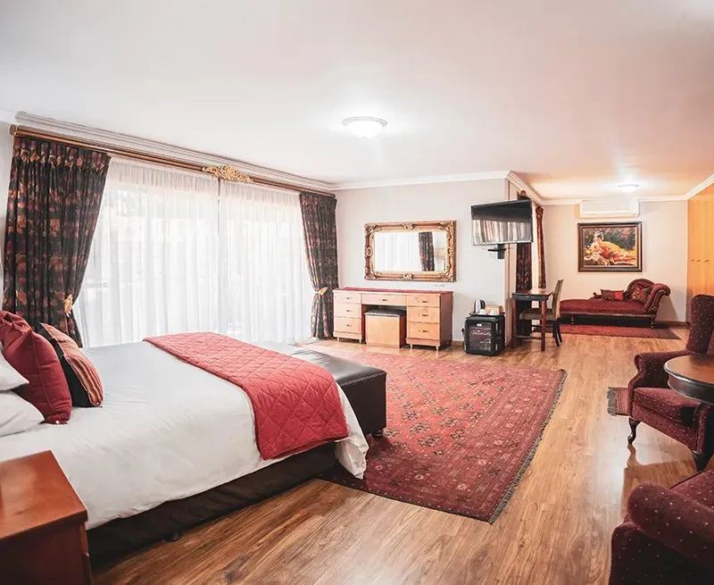 Elegant bedroom with large bed red accents and wooden flooring