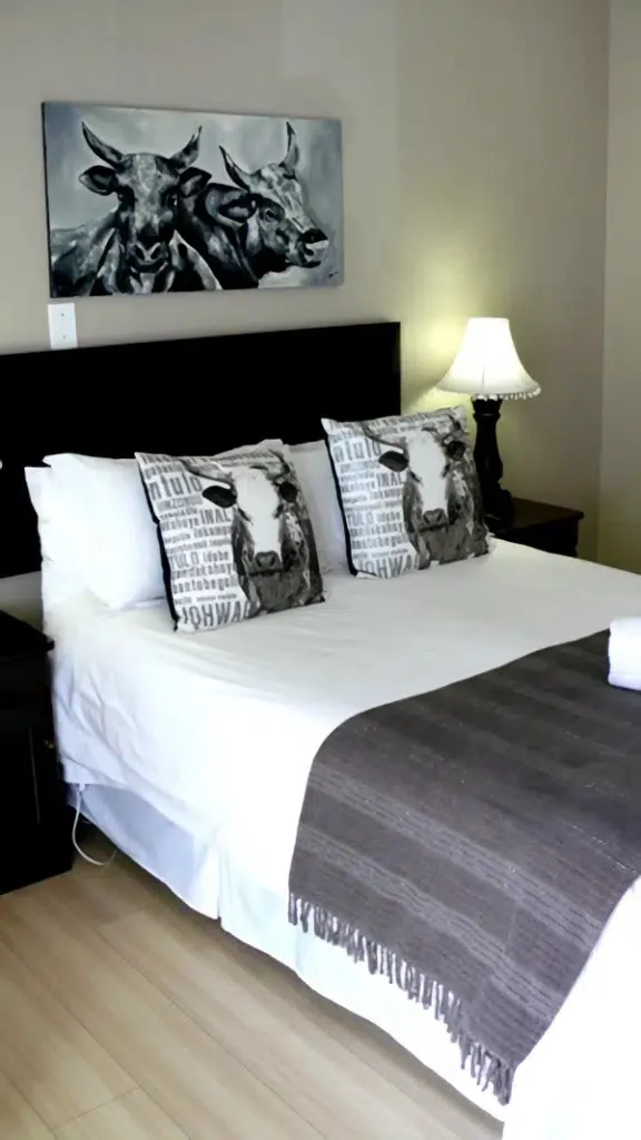 Bedroom with a bed cowthemed pillows and a matching wall art piece